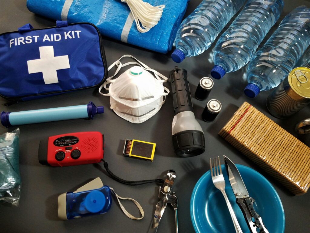 "Fotografía de un kit de emergencia recomendado por la Unión Europea, con agua potable, alimentos no perecederos, linterna, radio, botiquín de primeros auxilios, pilas, documentos y dinero en efectivo, dispuestos sobre una mesa.