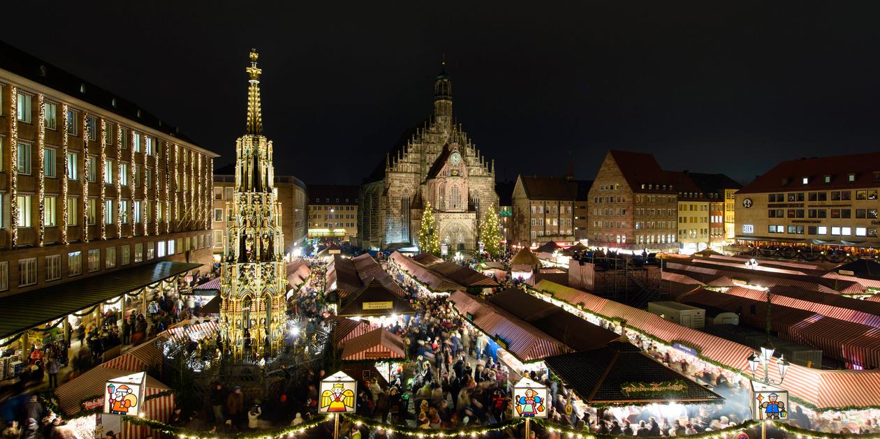 Puestos tradicionales del Christkindlesmarkt de Núremberg con luces y decoraciones navideñas.